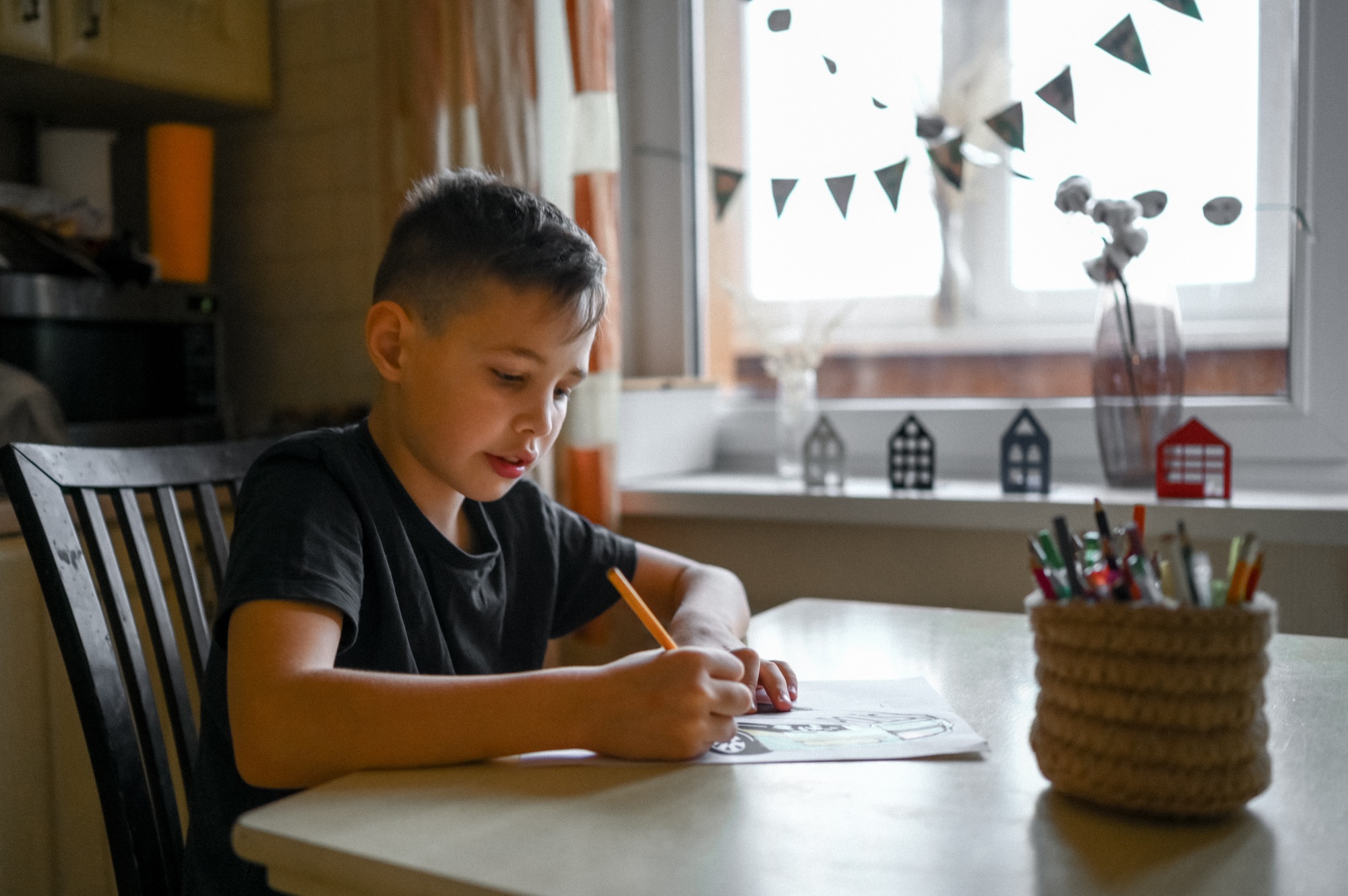 A 10-year-old boy draws a drawing with colored pencils
