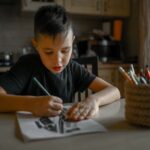 A 10-year-old boy draws a drawing with colored pencils