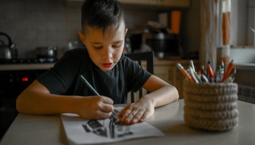 A 10-year-old boy draws a drawing with colored pencils