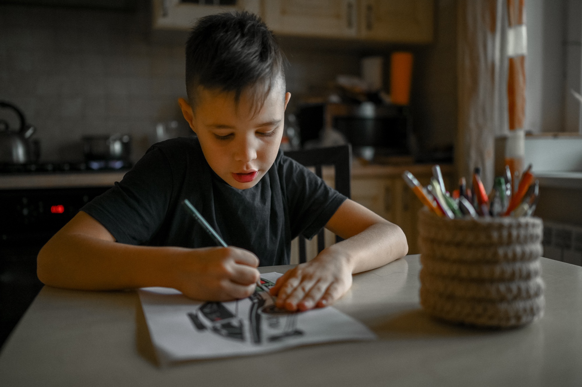 A 10-year-old boy draws a drawing with colored pencils