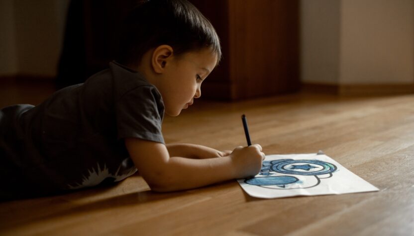A little boy draws a drawing with colored pencils