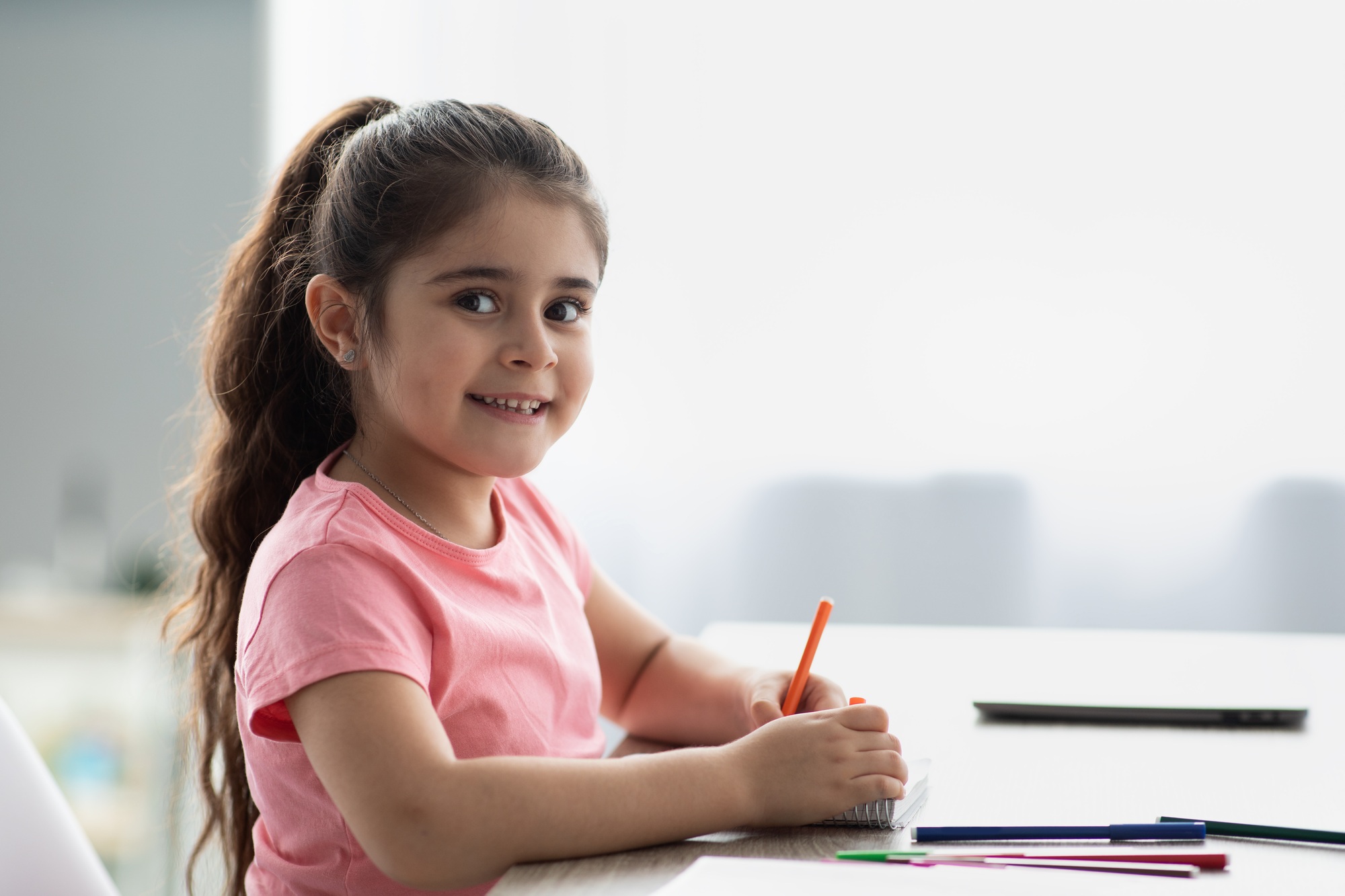 Beautiful Little Girl Siting At Table And Drawing With Colorful Pencils