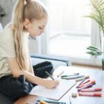 Child girl drawing with colorful pencils