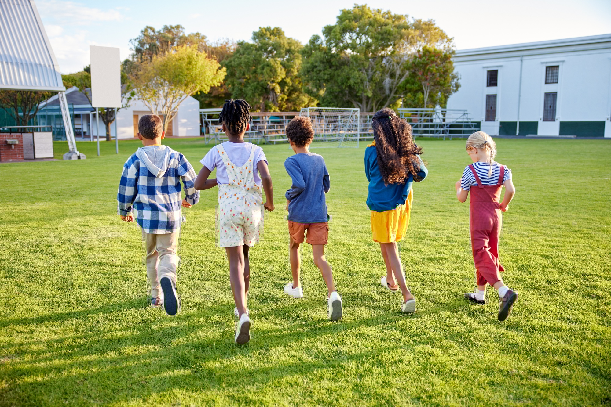 Children running together in park at sunset