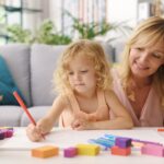 Girl and mother drawing together at home