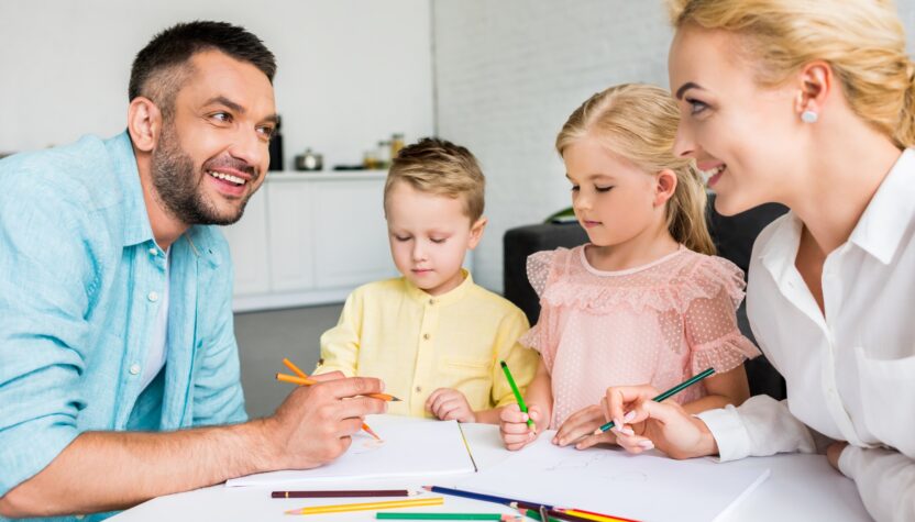 happy parents with two little kids drawing with colored pencils at home