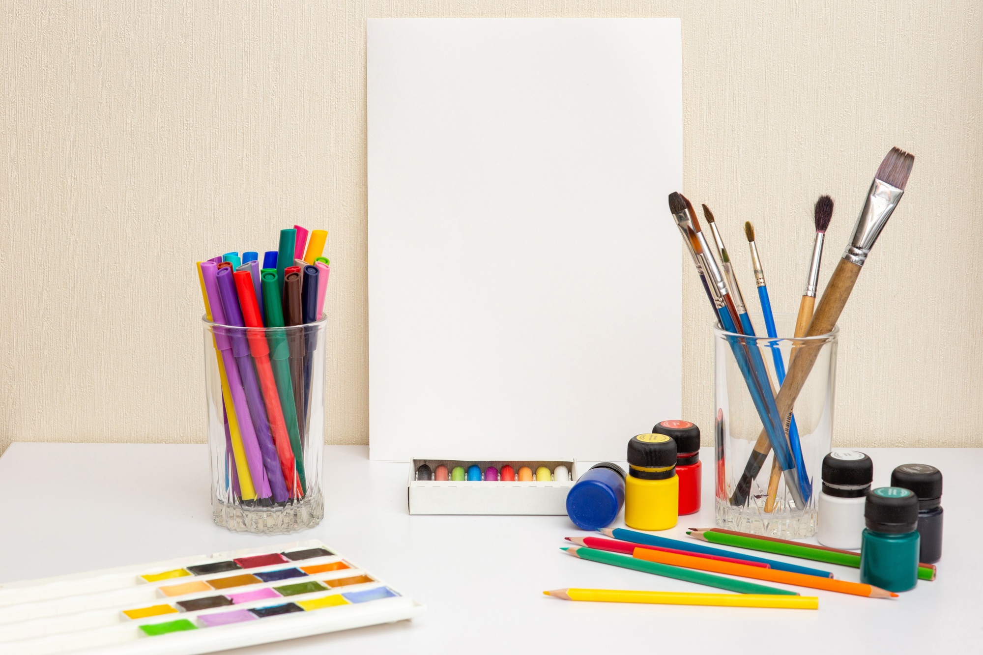 White paper, paintbrushes and colorful drawing supplies on white