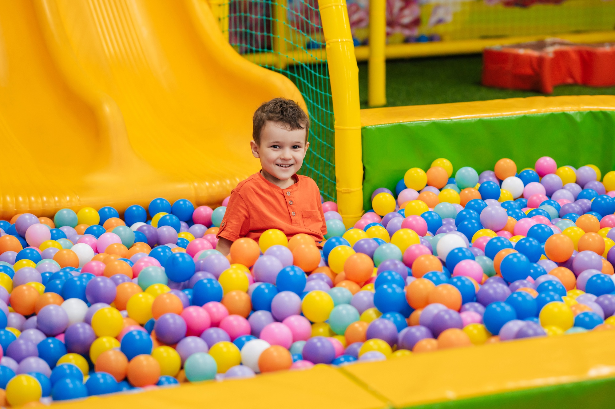 A happy baby boy is playing in a dry pool with colorful balls. Game entertainment center for