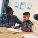 Drawing together. African american father with his young son at home