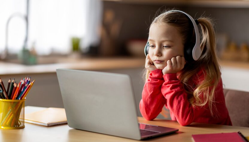 E-Learning Problems. Bored Little Girl In Wireless Headphones Looking At Laptop Screen