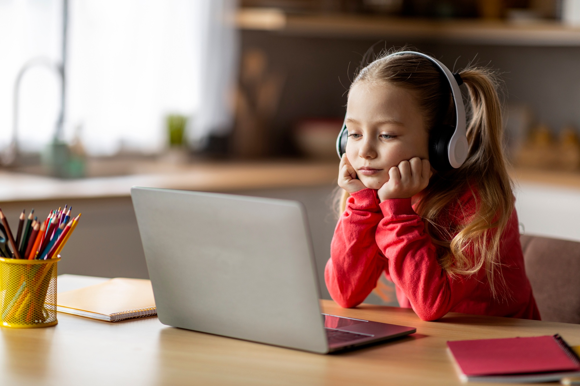 E-Learning Problems. Bored Little Girl In Wireless Headphones Looking At Laptop Screen