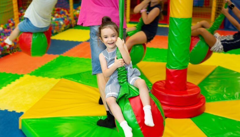 Girl rides on a carousel in a children's play center