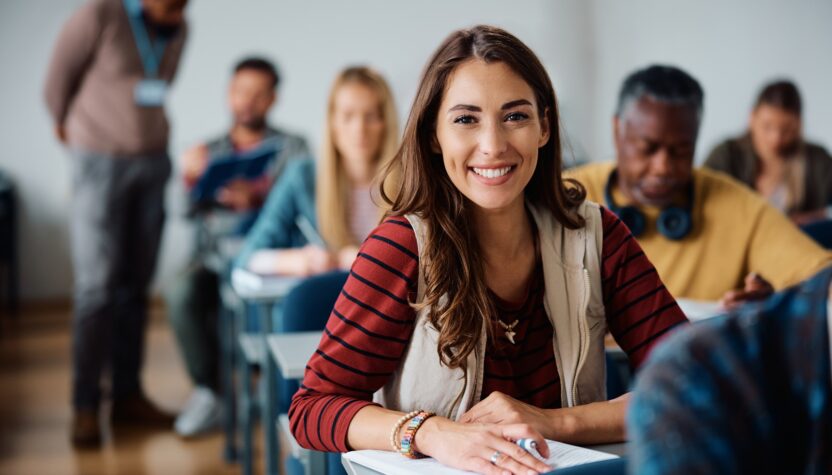 Happy female student learning in the classroom and looking at camera.