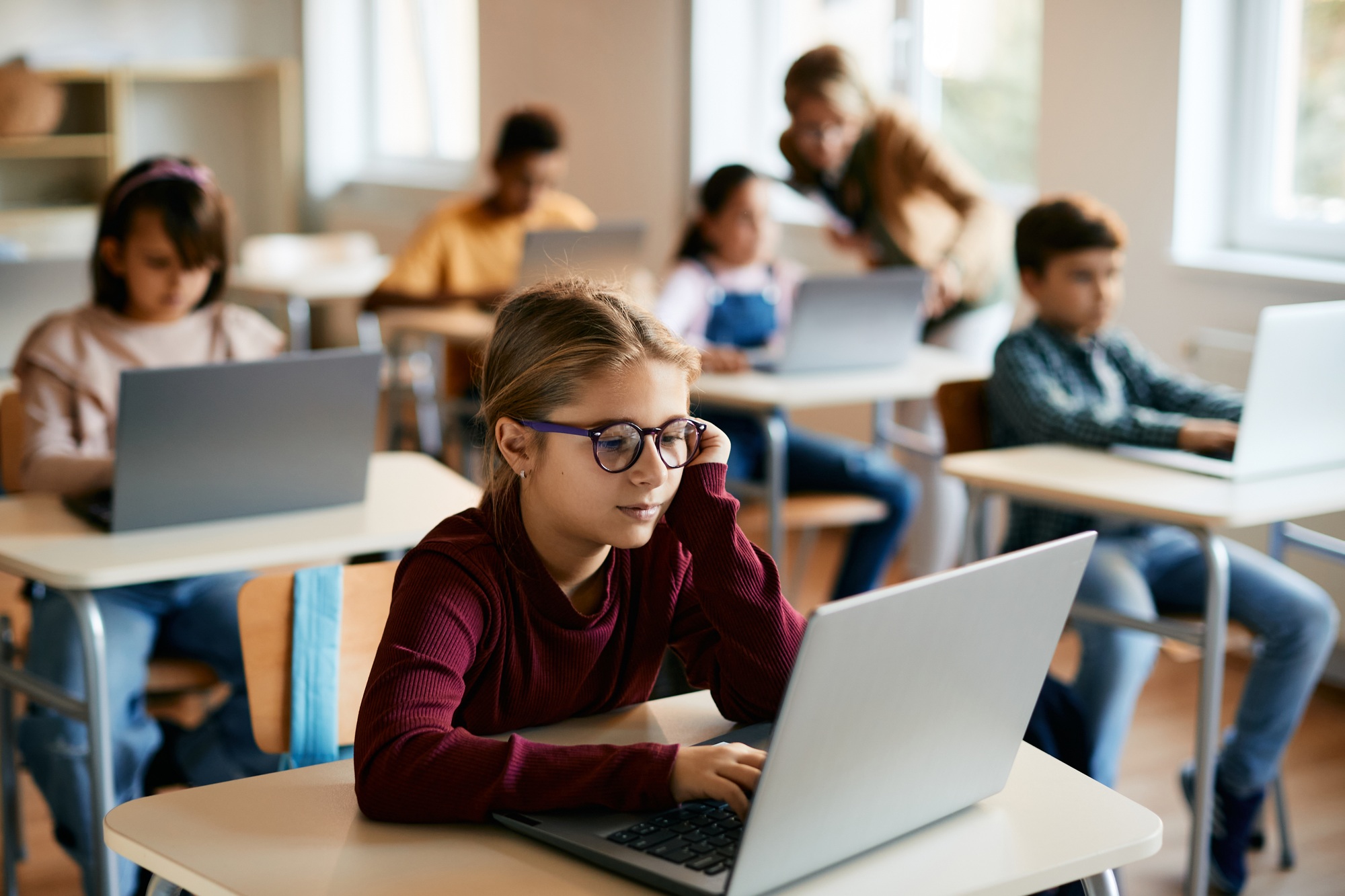 Little girl e-learning on laptop in the classroom at school.