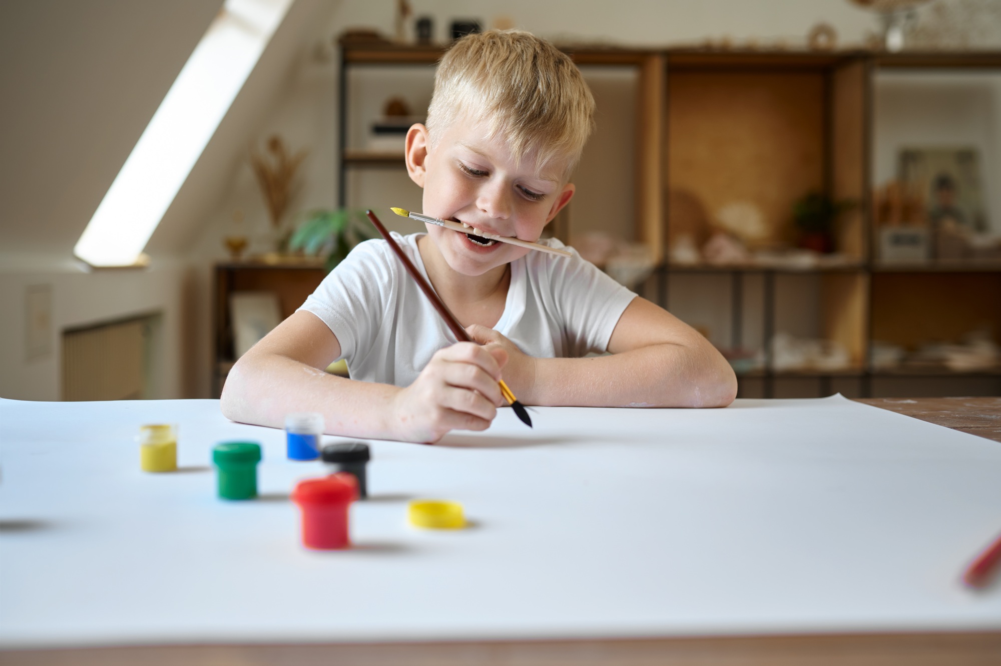 Male child drawing with gouache, kid in workshop