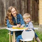 Mother and kid happily drawing in backyard. Early years. Baby development.