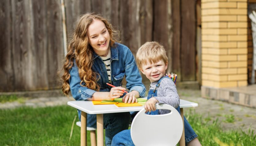 Mother and kid happily drawing in backyard. Early years. Baby development.