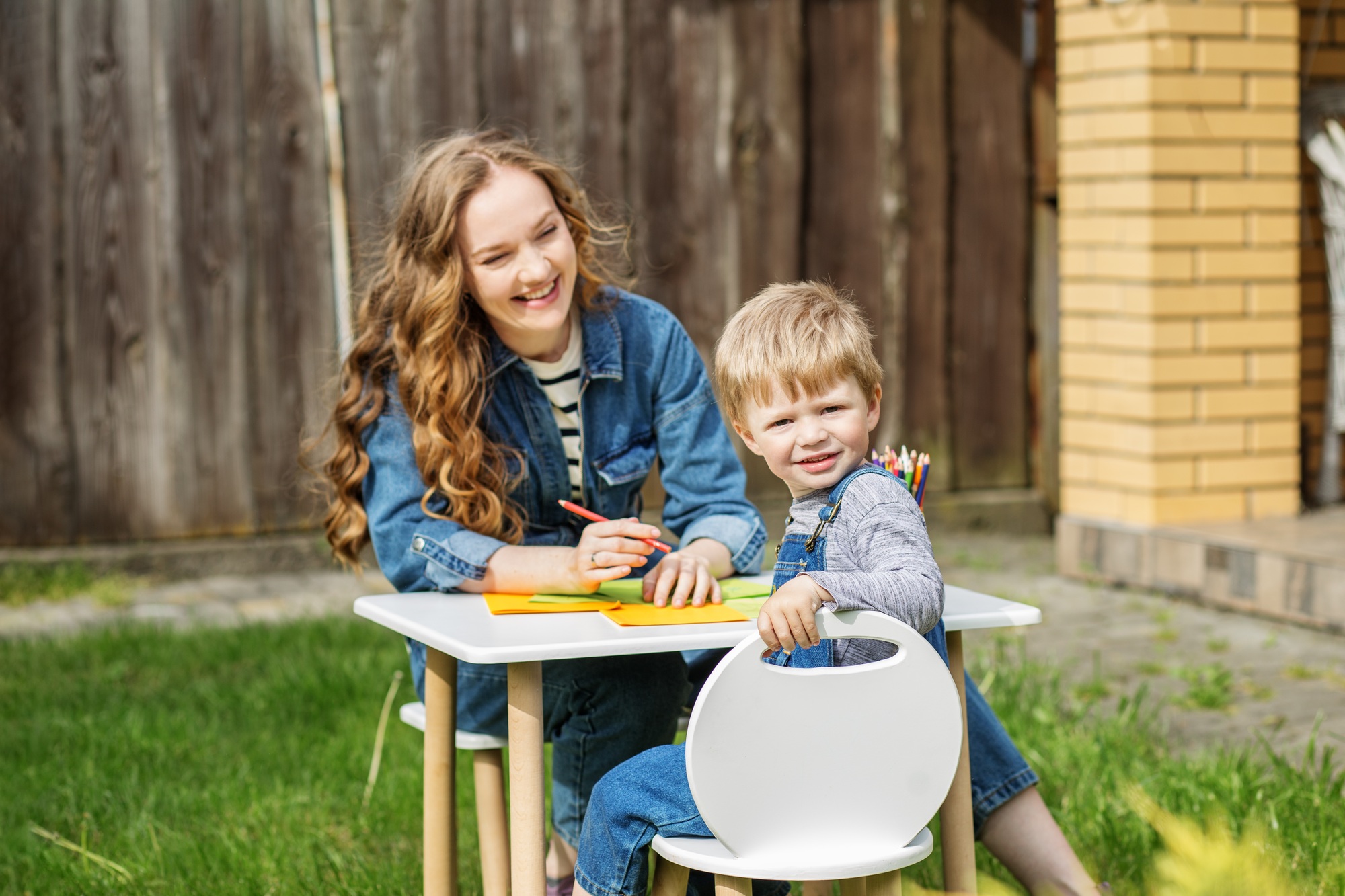 Mother and kid happily drawing in backyard. Early years. Baby development.