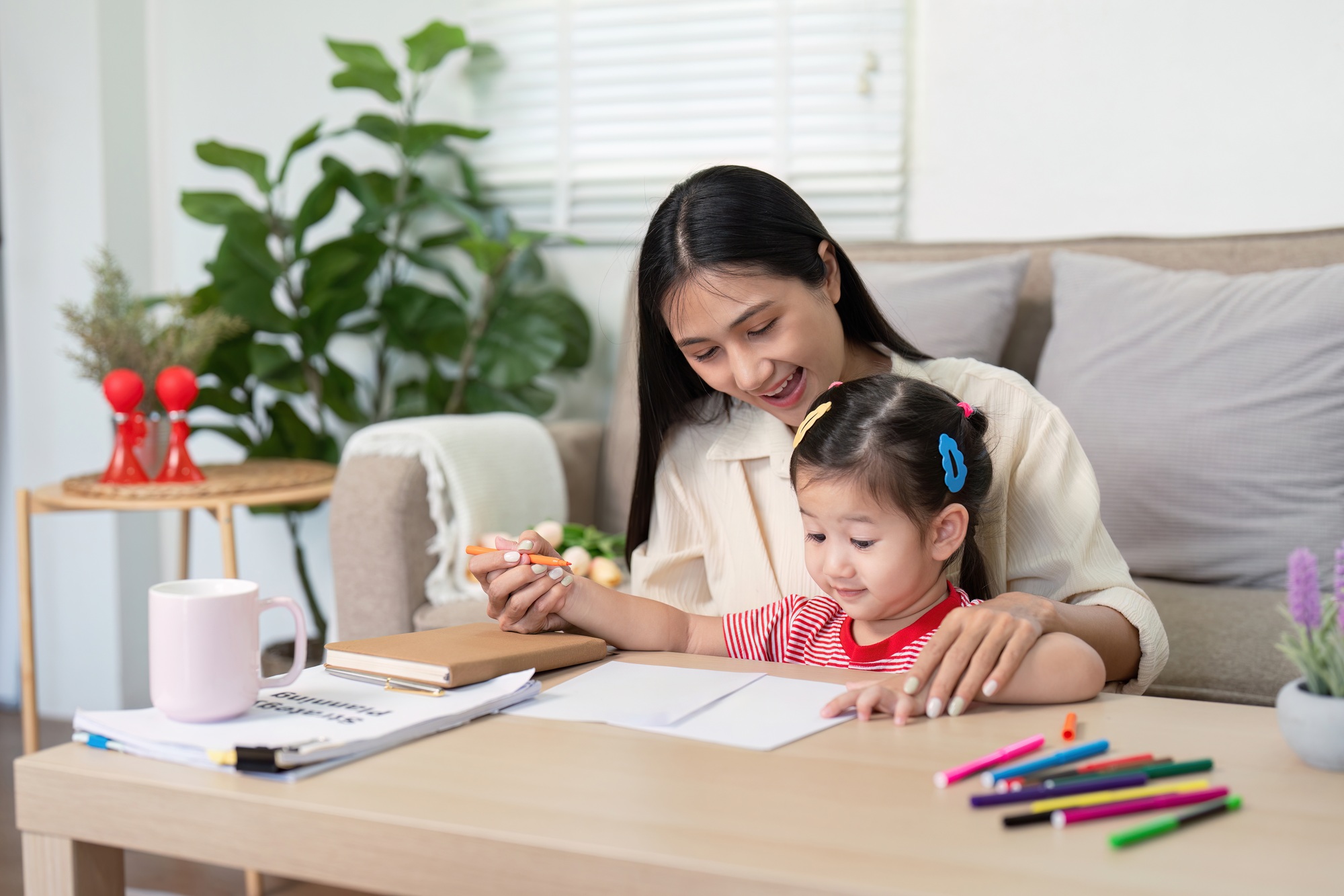 Mother guiding daughter in drawing activity at home