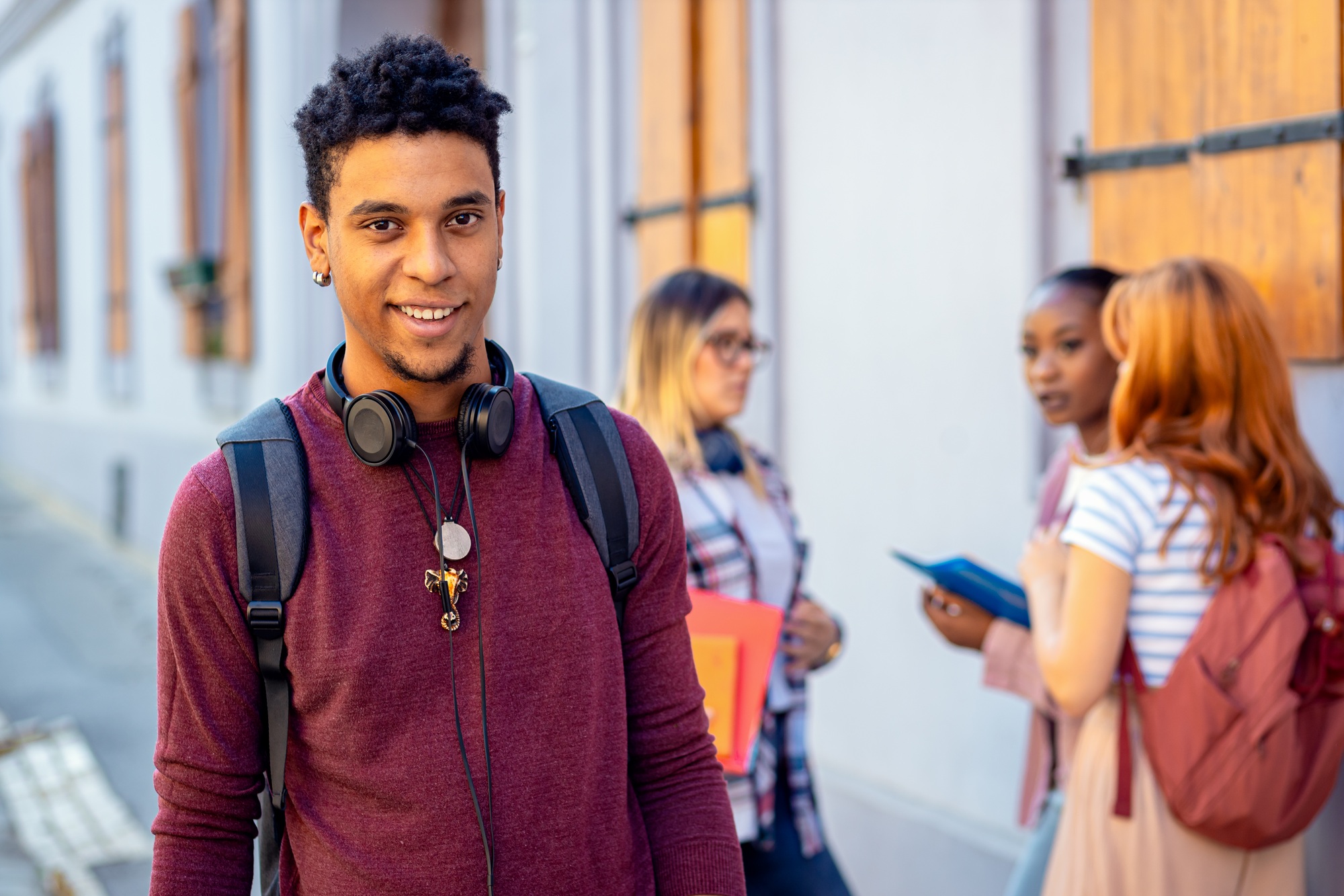 Portrait of smiling African American male student with friends looking at camera.