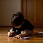 A little boy 5 years old draws a drawing with colored pencils