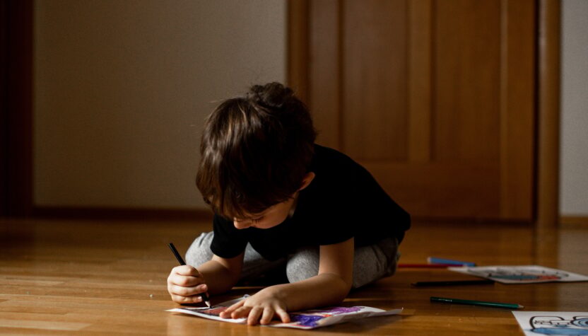 A little boy 5 years old draws a drawing with colored pencils