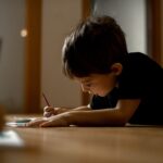 A little boy draws a drawing with colored pencils