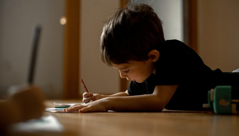 A little boy draws a drawing with colored pencils