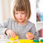 Little girl cutting out yellow modeling clay