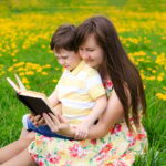Mother and son reading a book in nature