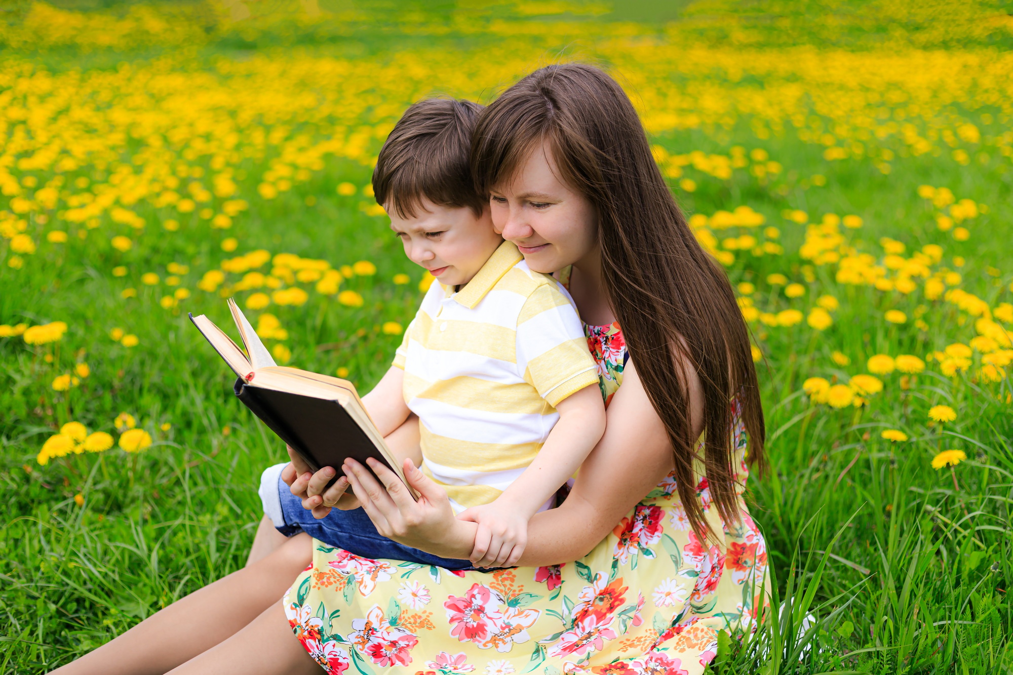 Mother and son reading a book in nature