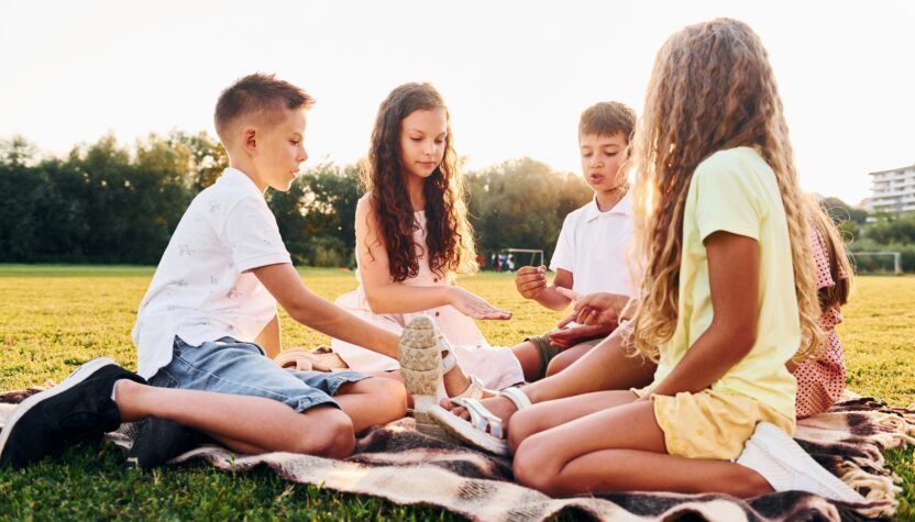 Playing games. Group of happy kids is outdoors on the sportive field at daytime