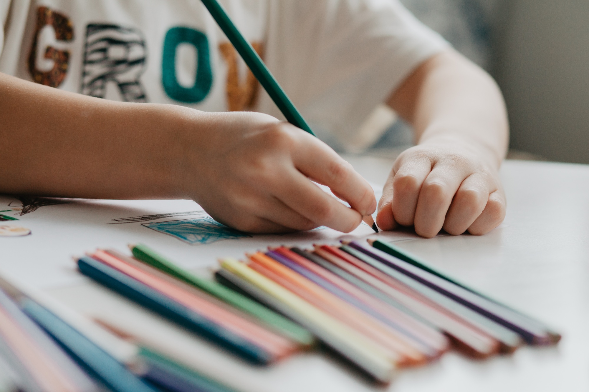 The boy draws with pencils at the kitchen, closeup