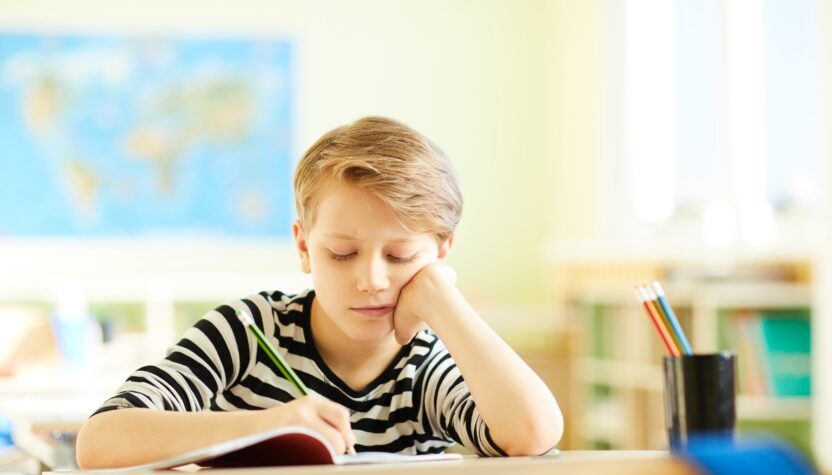 Tired boy drawing in workbook