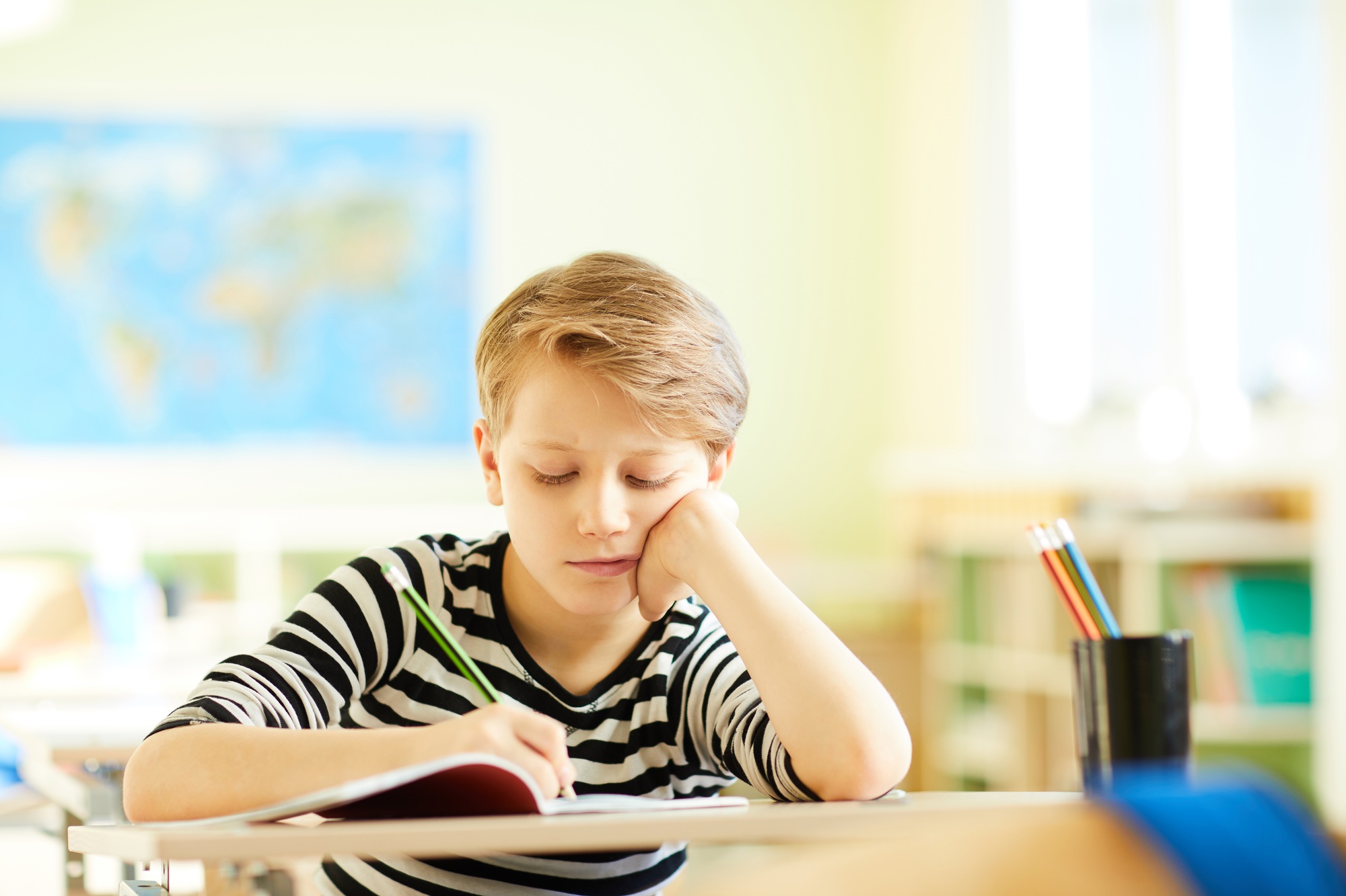 Tired boy drawing in workbook