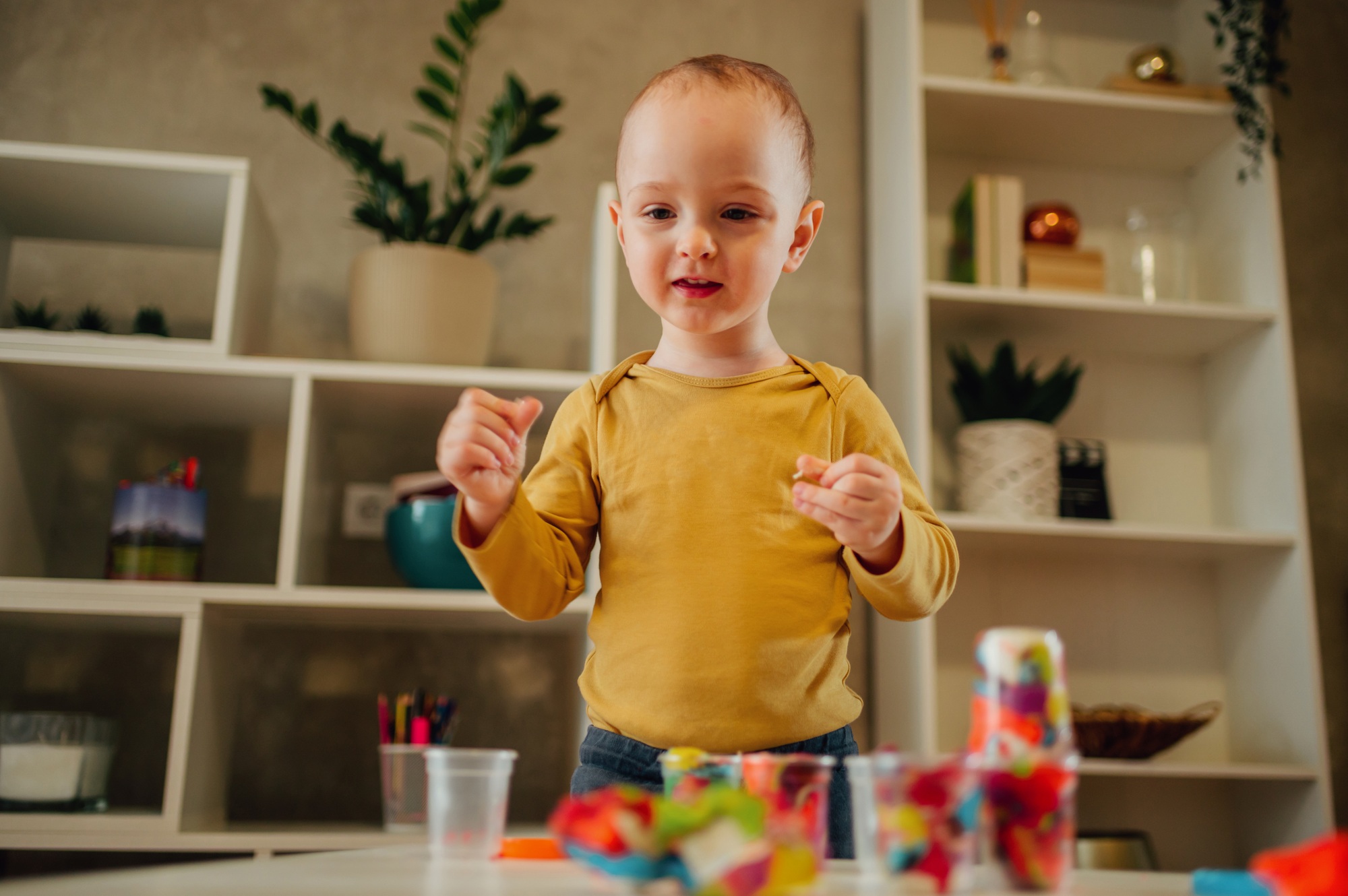 Toddler child playing with modeling clay in a kindergarten or ho